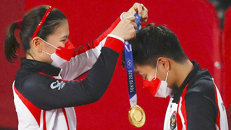 Greysia Polii saat mengalungkan medali emas kepada pasangannya, Apriyani Rahayu, dalam prosesi penyerahan medali kepada pemenang ganda putri bulutangkis Olimpiade Tokyo.